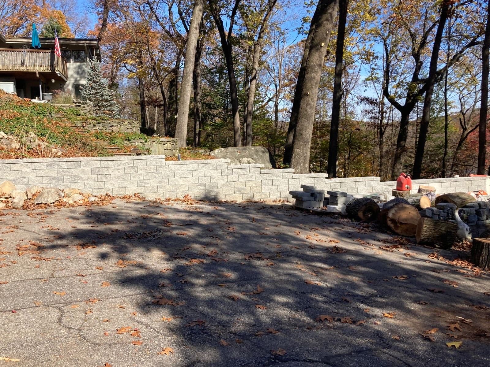 Finished segmental block retaining wall stepping along a driveway below a hillside home