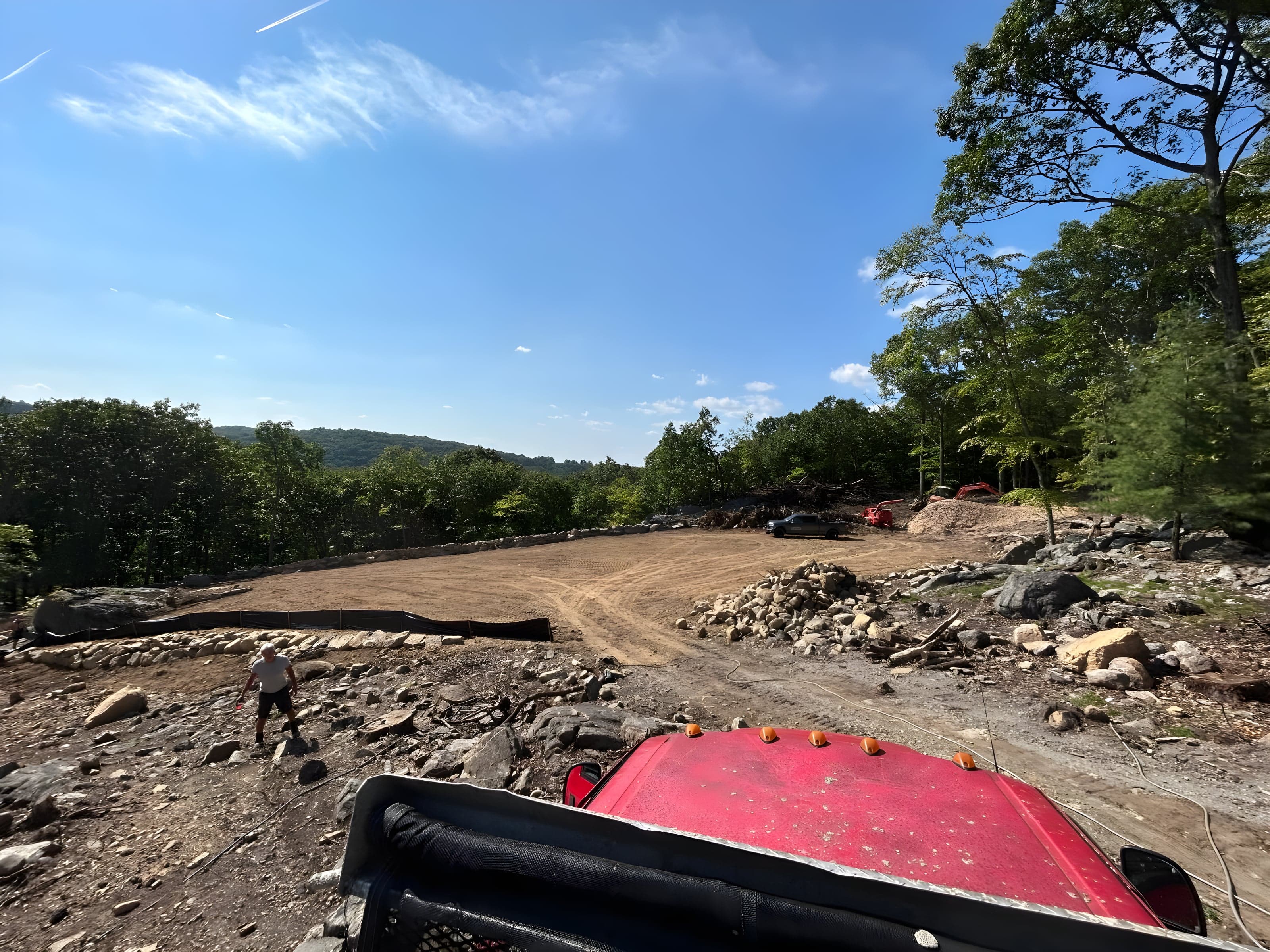 Hilltop building pad graded smooth with silt fence and boulder edging