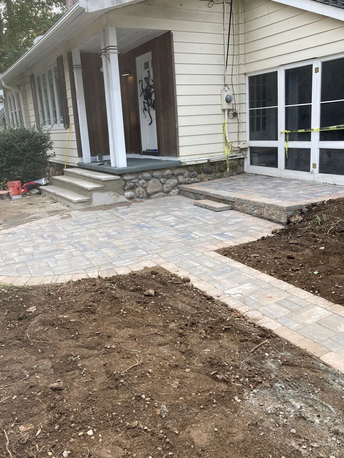 New paver walkway and porch landing mid install at a stone foundation home