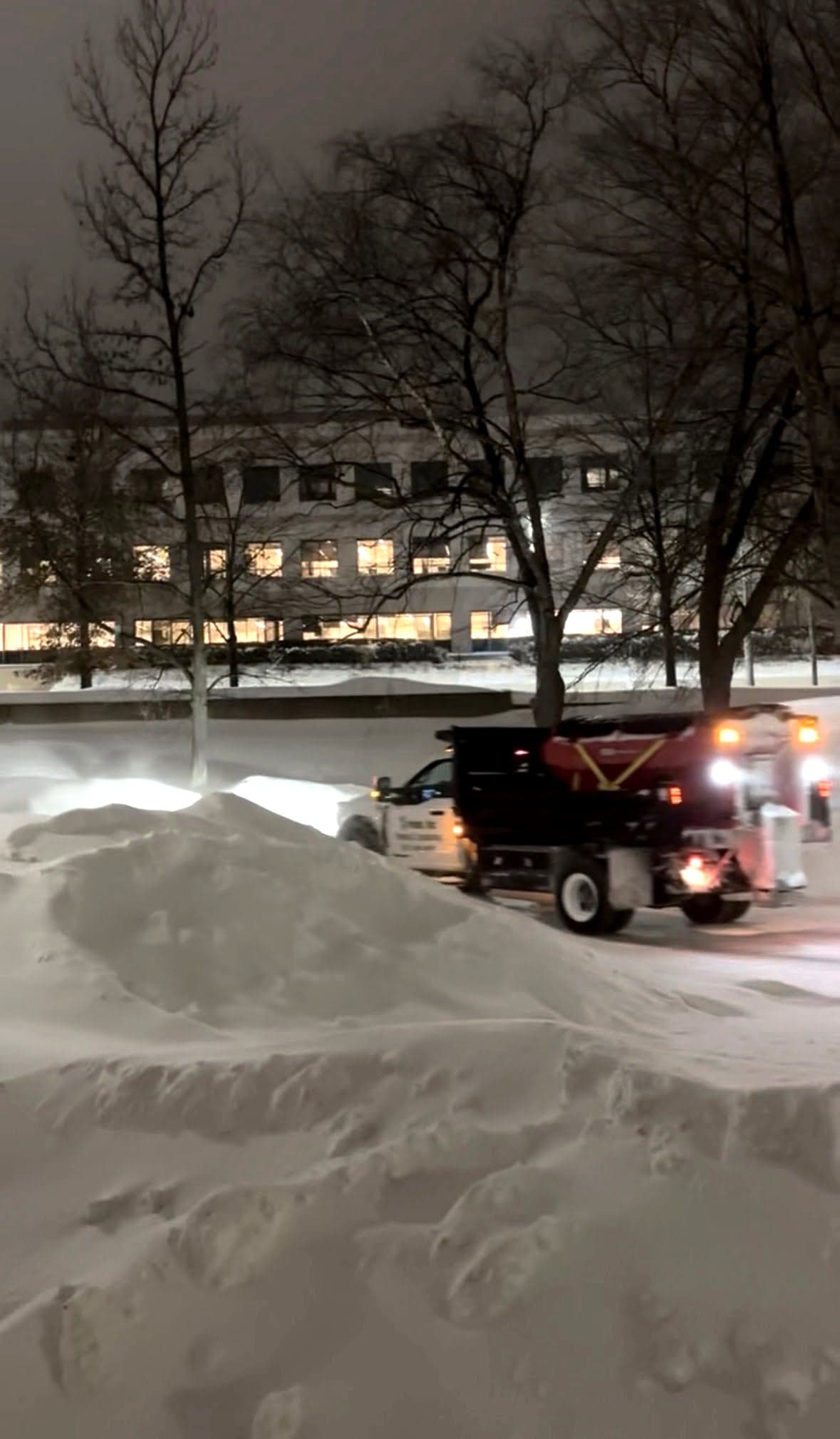 Salt spreader truck working a snowed in commercial lot outside an office building