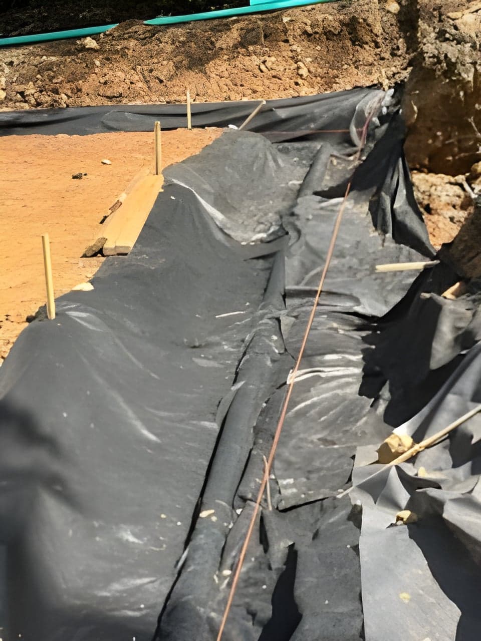 Filter fabric lining a staked out stormwater basin excavation