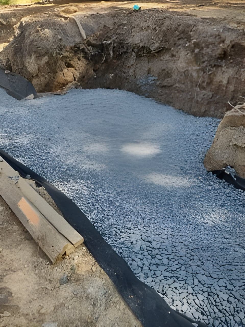 Excavated stormwater basin filled with clean drainage gravel over filter fabric