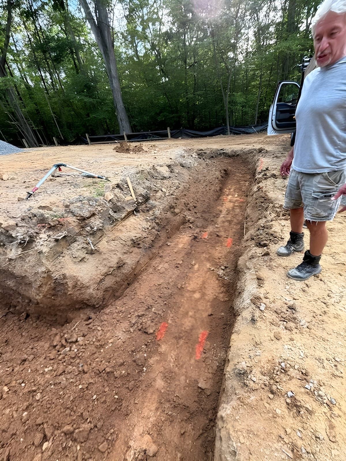 Open trench cut along marked utility lines with the crew checking the run